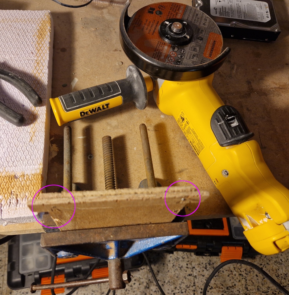 Une grande meuleuse d'angle jaune est posée sur le plan de travail et les vis ont été rabottées