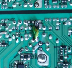 Un bout de circuit imprimé où on voit clairement un tout petit fil qui ponte deux contact, la gaine est à moitié brûlée